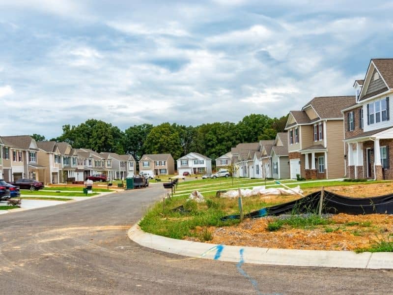 Aerial view of a residential subdivision under development showing new houses, roads, grading work, and drainage areas during neighborhood construction planning.